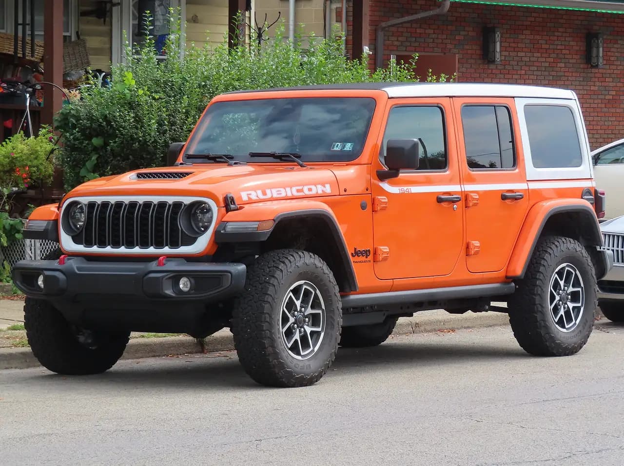 Orange 2026 Jeep Wrangler Rubicon 4-door (JL) with white hardtop, front three-quarter view