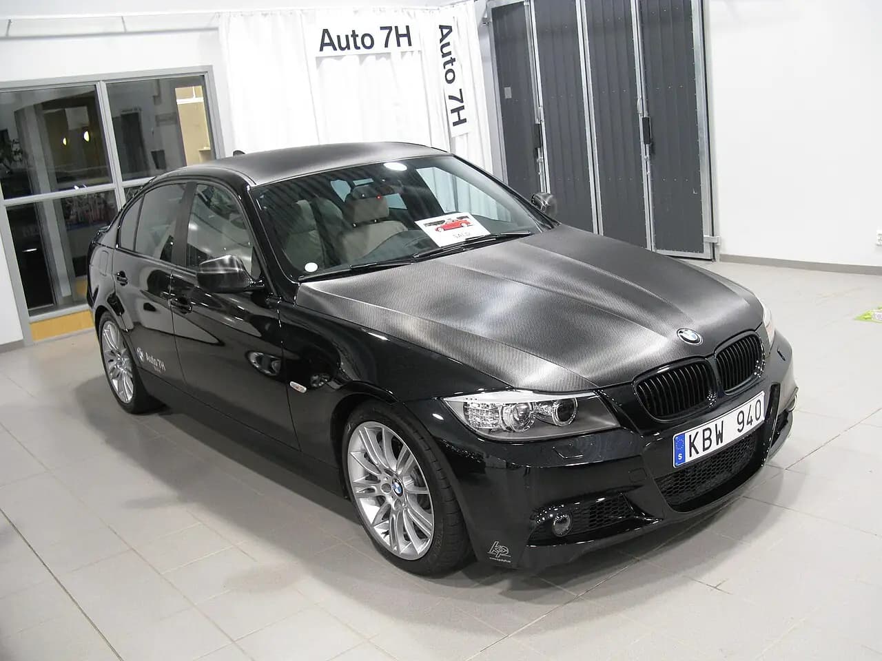 Black BMW 335i M Sport sedan (E90 LCI) with carbon-look bonnet wrap, front three-quarter view