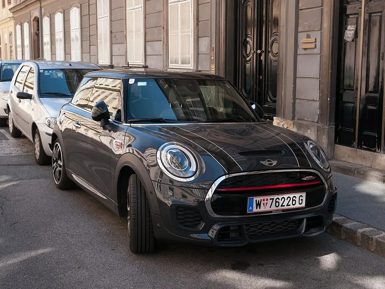 Black Mini John Cooper Works 3-door hatch (F56, pre-LCI) with white bonnet pinstripes, front three-quarter view