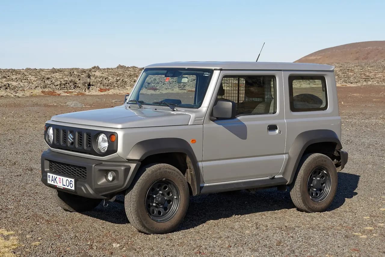 Silver Suzuki Jimny (JB74) 3-door on a gravel car park in Iceland, front three-quarter view
